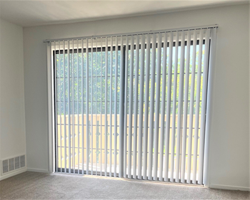 A large window with white vertical blinds in a living room